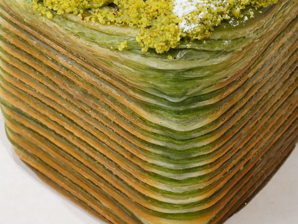 Emerald Pistachio, cận cảnh các lớp bột màu xanh · Emerald Pistachio, close-up of green laminated layers with a green crumble on top