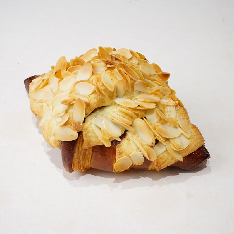Almond Croissant · Bánh viennoiserie phủ hạnh nhân lát nướng vàng · Viennoiserie topped with golden toasted sliced almonds