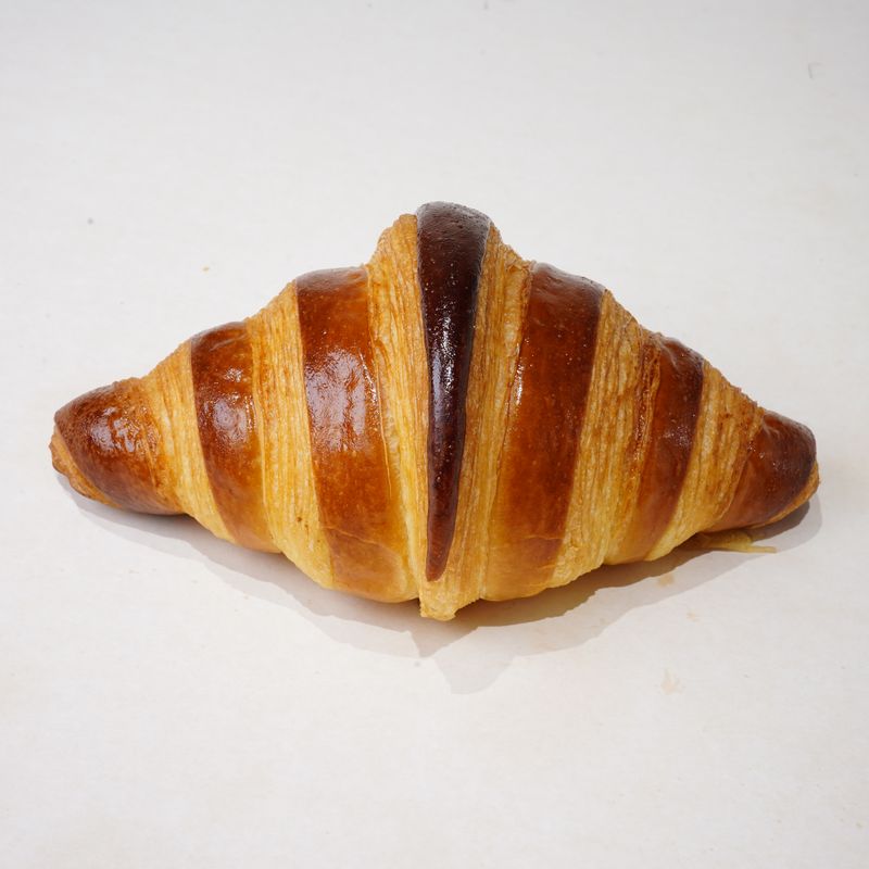 Croissant · Bánh croissant vàng nâu, nhìn từ bên cạnh · Golden-brown croissant, side view