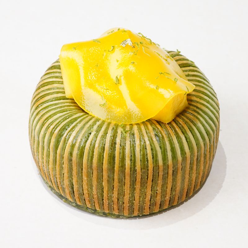 The Earl's Mango · Bánh ngàn lớp tròn sọc xanh lá, mặt trên phủ lớp nhân màu vàng · Round green-striped laminated pastry topped with a yellow filling